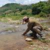 man stooping in a stream