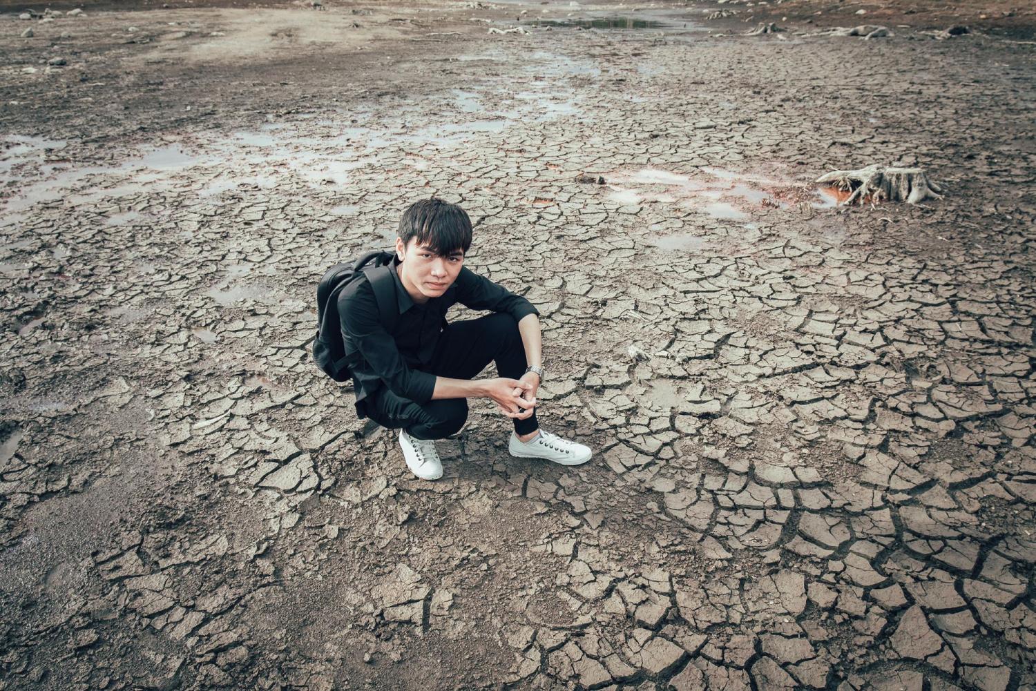 Person kneeling on dry cracked ground