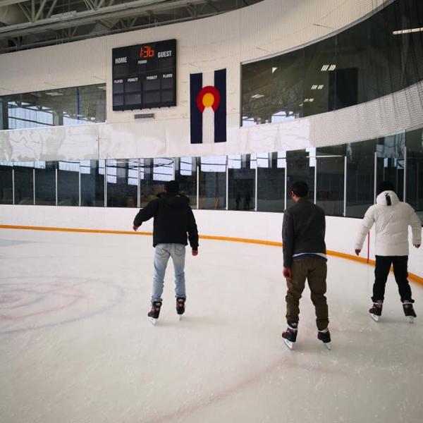 View of three grad students ice skating from behind