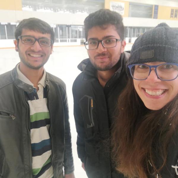 Three grad students smiling at ice rink