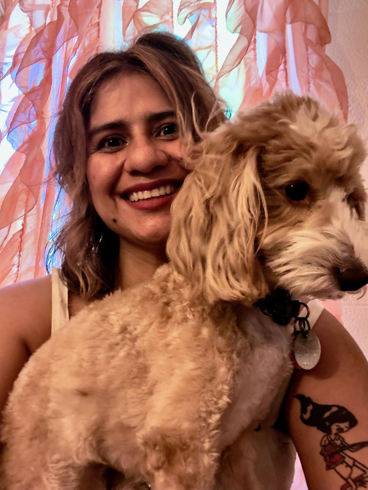 A woman smiling with a dog on her lap partially obscuring her face