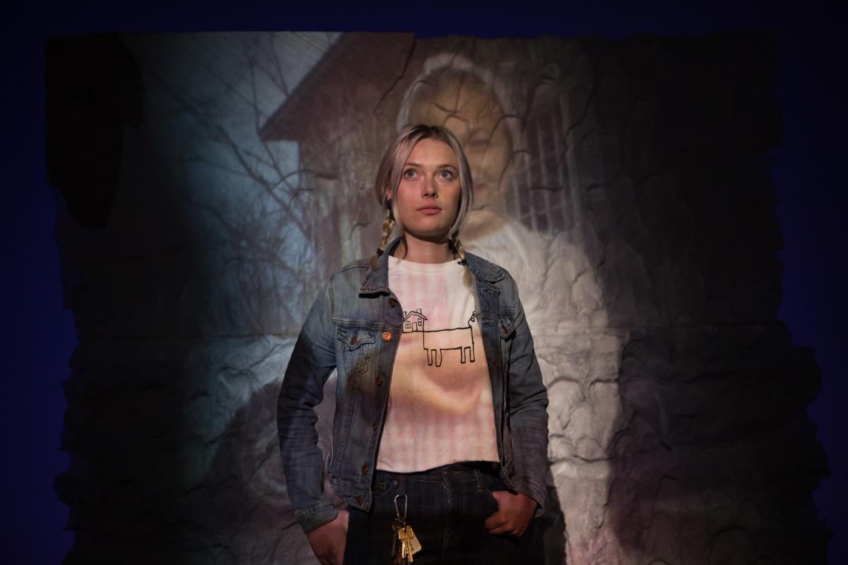 Student in an art exhibition with a screen showing something behind her