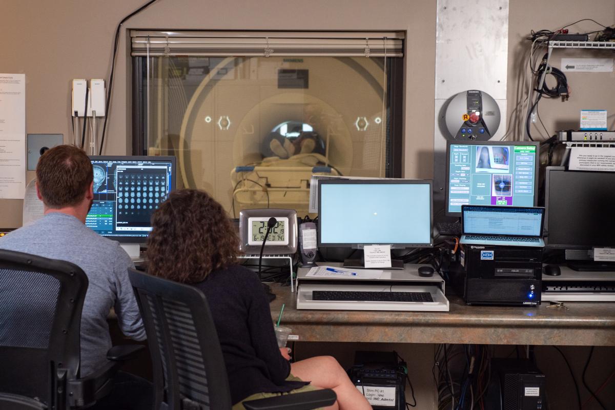 Two scientists sitting in front of an MRI machine