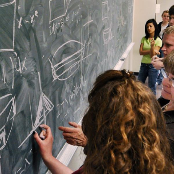 Students working on math problems on a chalkboard 