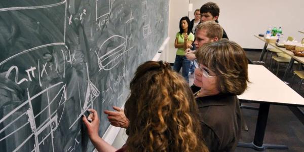 Students working on math problems on a chalkboard 