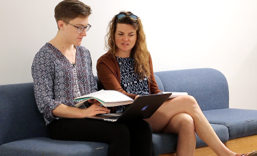 Picture of Sarah working on a laptop and notebook with student