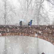 Students walking across Varsity Pond bridge in the snow