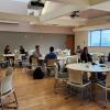 Students seated at tables eating burritos with a powerpoint in the back that says "Graduate Student Appreciation Week"
