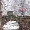 A person walking across Varsity Bridge with an umbrella as it snows hard.