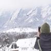 Student taking a picture of the snowy Flatirons