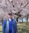 A photo of Ethan Bober with blooming trees behind him.