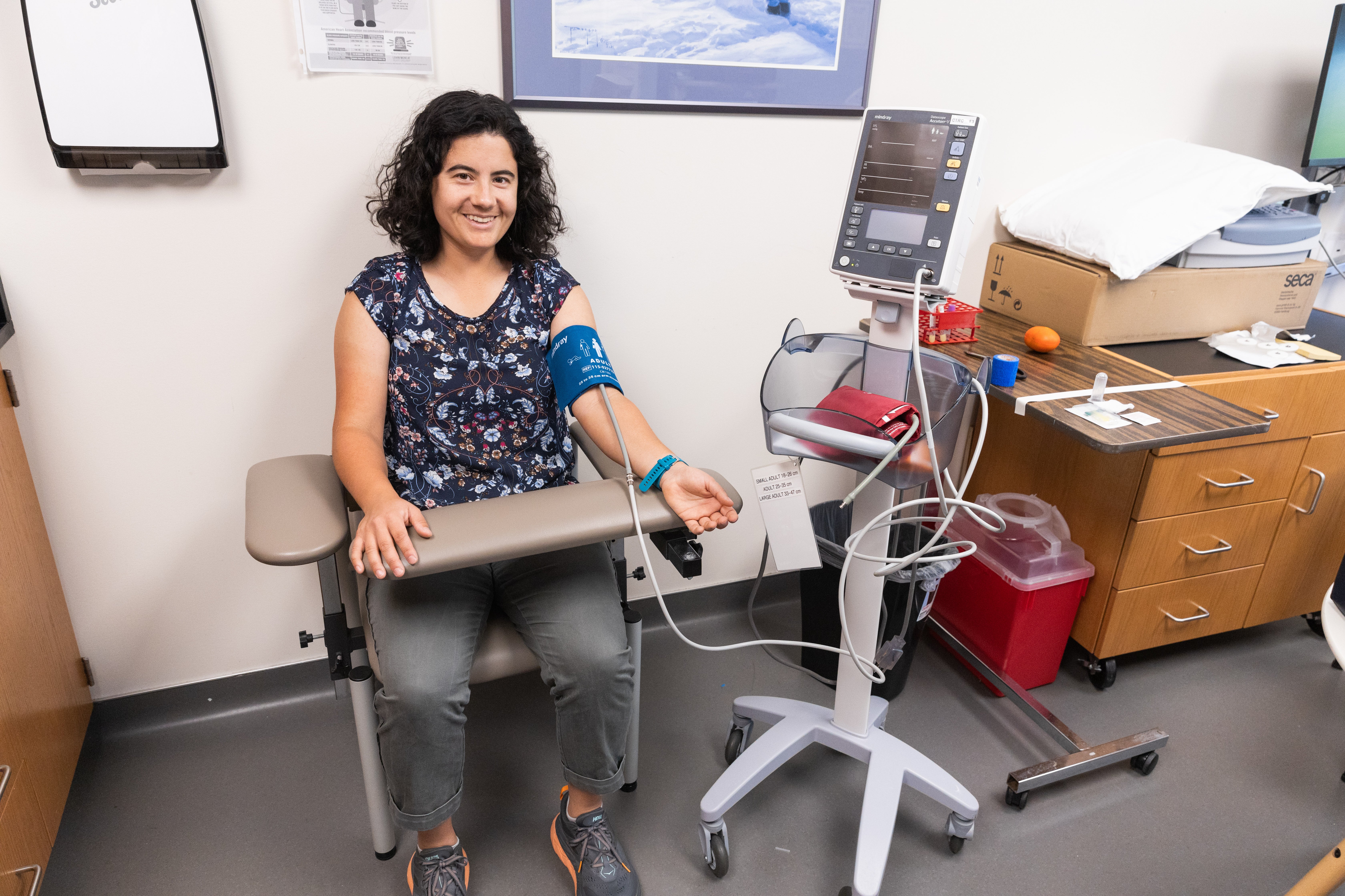 A woman sits with a blood pressure monitor