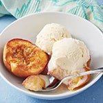 Baked peaches in a bowl with vanilla ice cream.