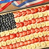 A fruit pizza with bananas and berries in an American flag arrangement