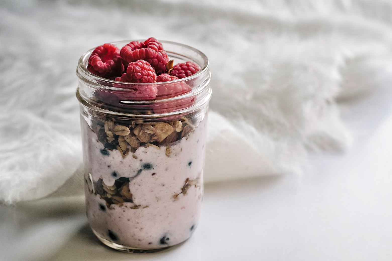 Jar of overnight oats topped with fresh raspberries.