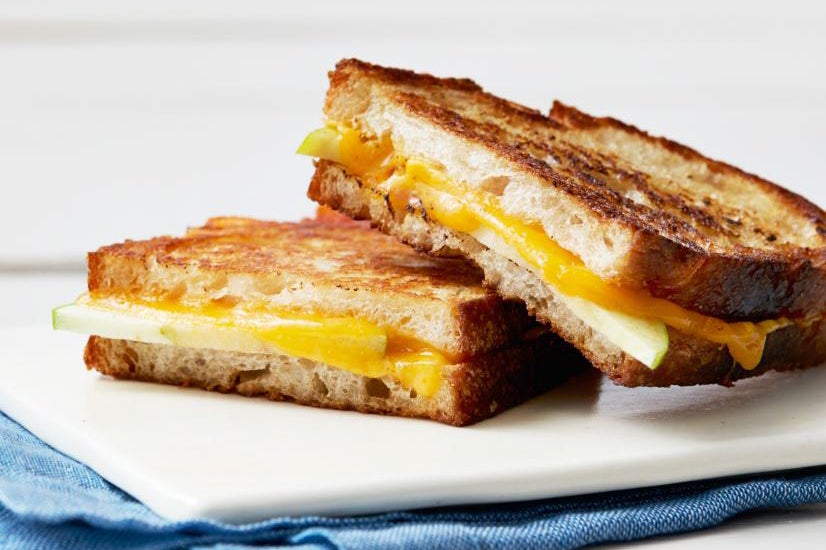 Photo of a grilled cheese sandwich with cheddar and apple slices on a plate.