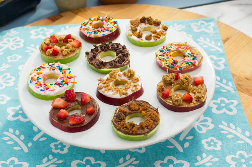 A variety of apple rings with different toppings on a tray.