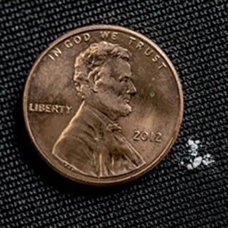 Photo of 2 mg of fentanyl next to a penny for scale.