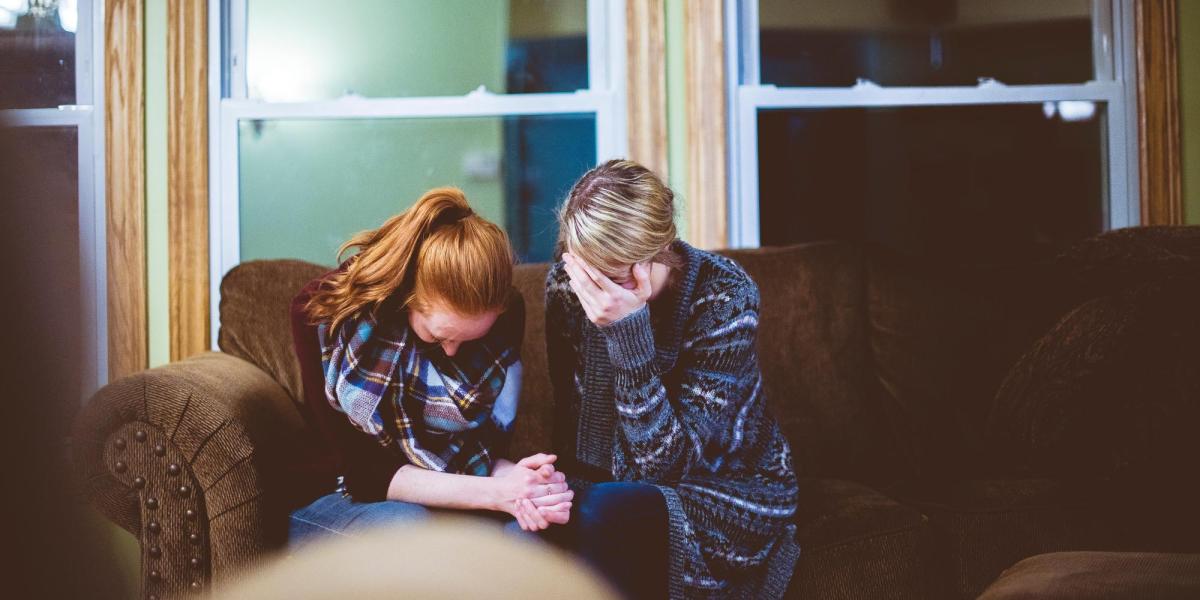 Two people sitting on couch with heads in hands