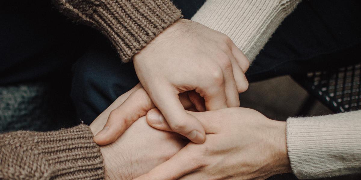 Close up of two sets of hands holding each other