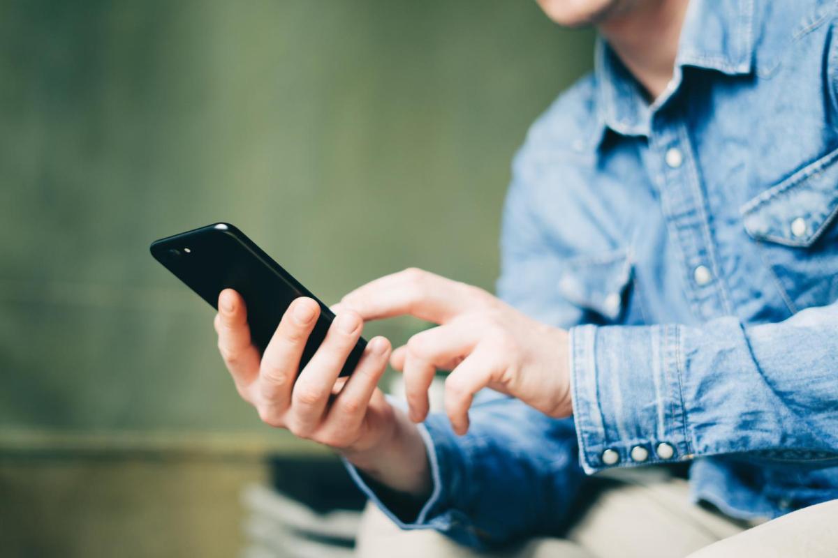 Photo of a person dialing a number on their cell phone.
