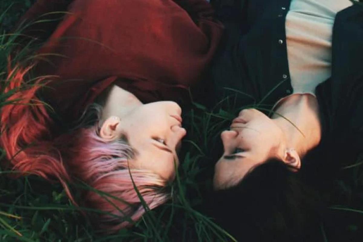 Photo of two people laying in the grass together.