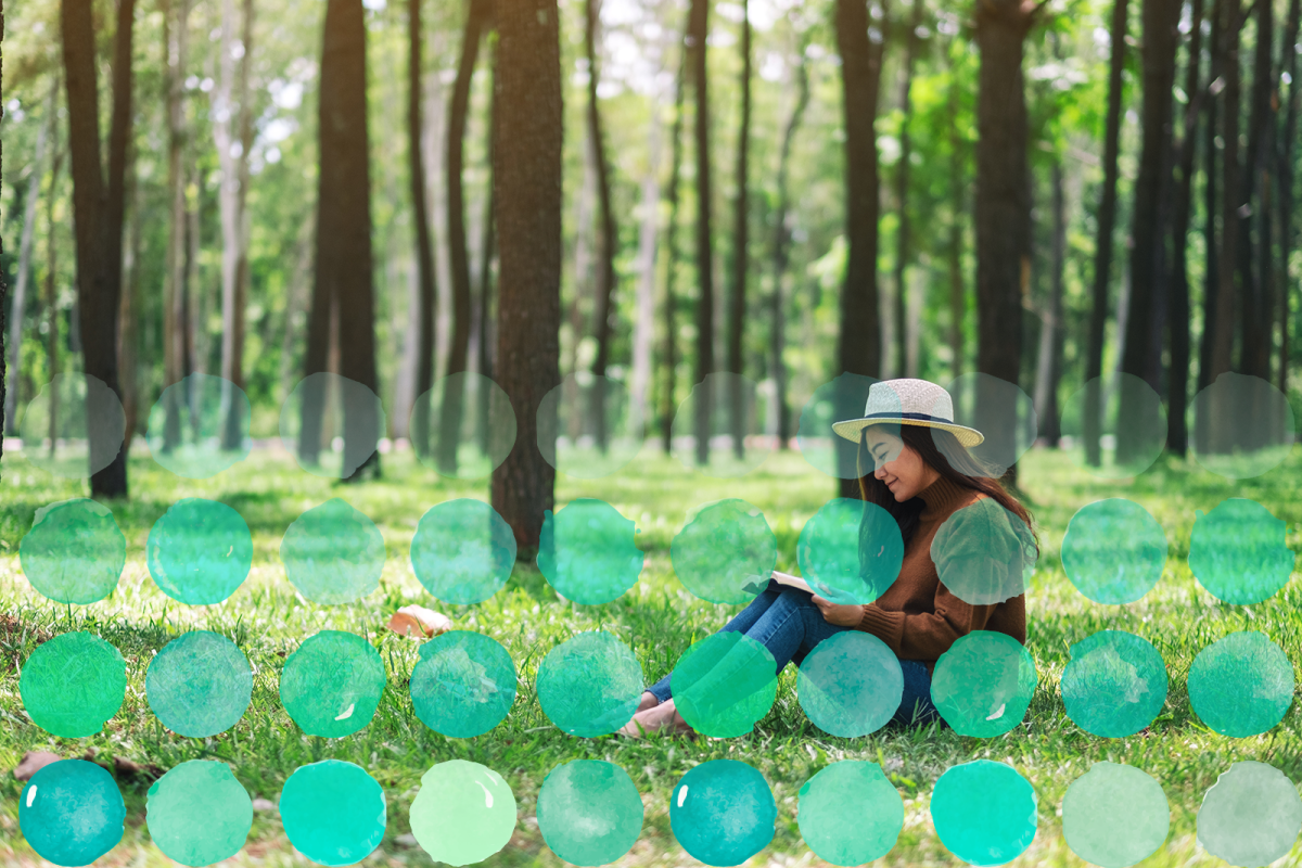 Photo of a student reading peacefully in a grassy area.