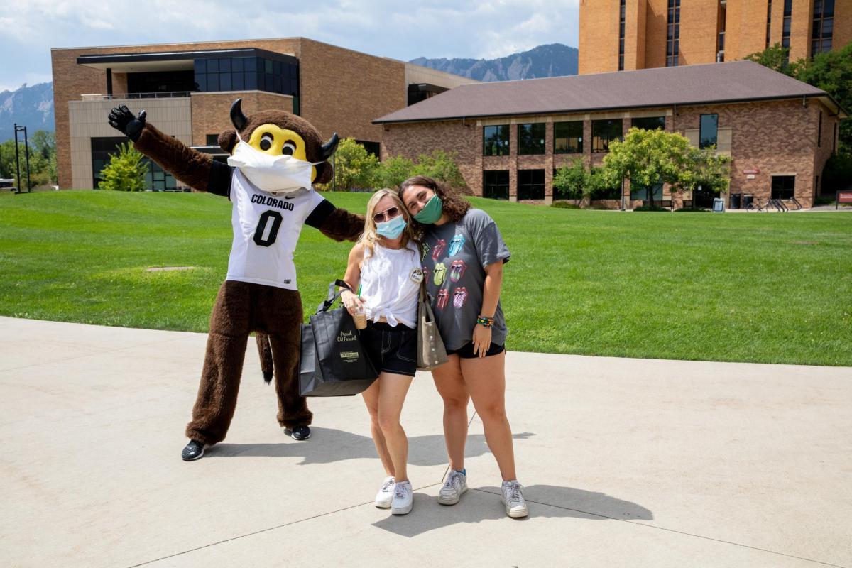 chip posing behind two new students, all are wearing masks