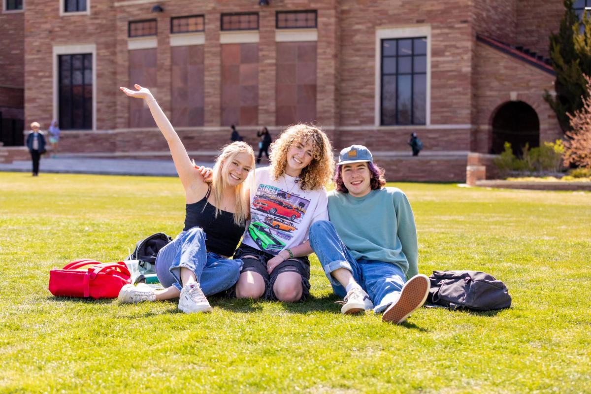 Three students hanging out at Farrand Field on a sunny day