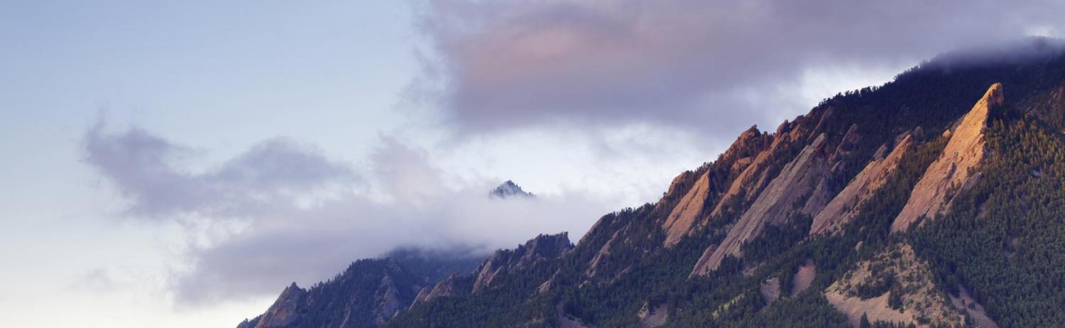 Photo of the flatirons at sunset with a foggy overcast.