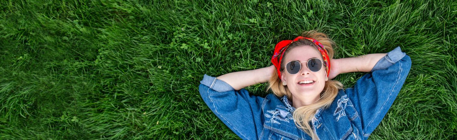 Photo of a girl lying on a lush patch of grass.