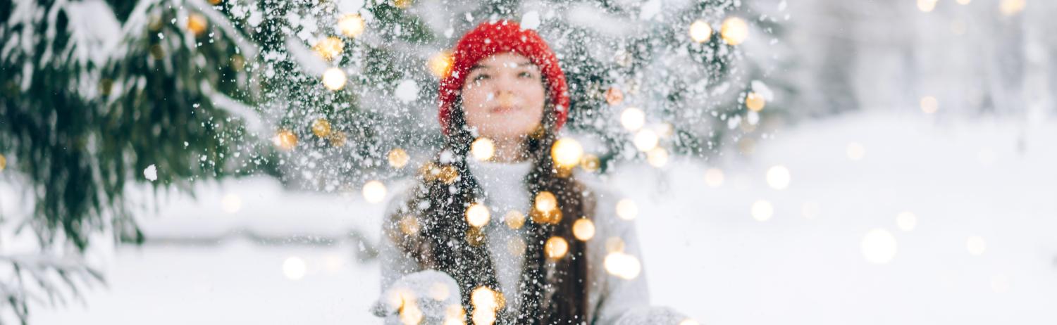 Photo of a student throwing snow into the air with twinkle lights.