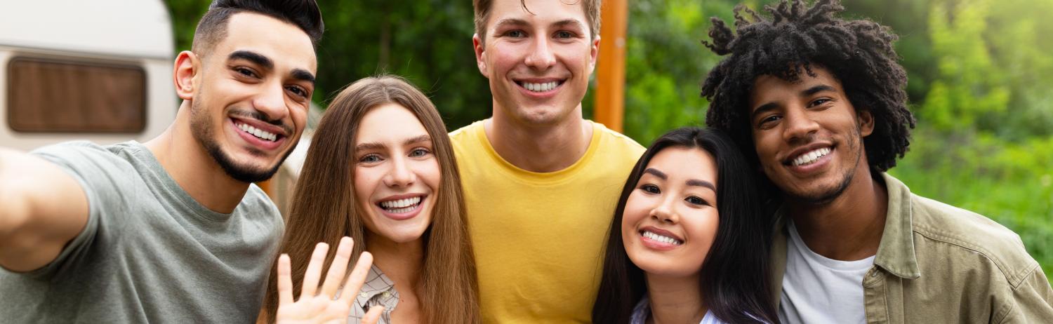 Group photo of friends taking a selfie while smiling outside.