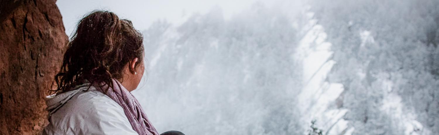 Photo of a solemn girl sitting in Chautauqua Park looking out over the snowy mountains.