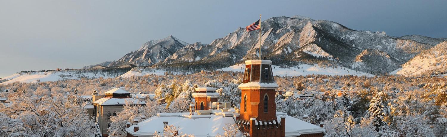 Aerial photo of Old Main in the early morning sun, covered in snow.