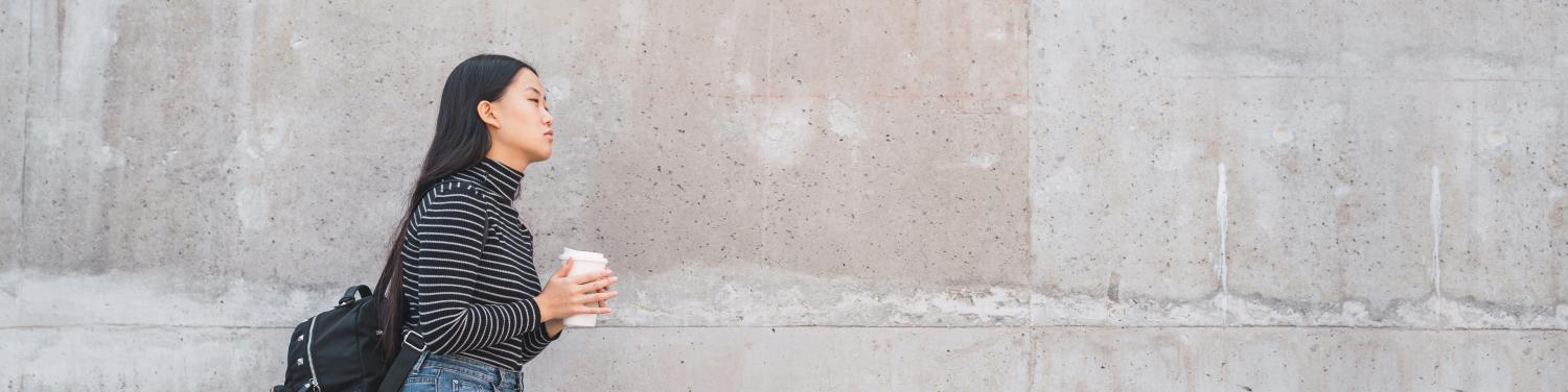 Student walking with a cup of coffee in hand
