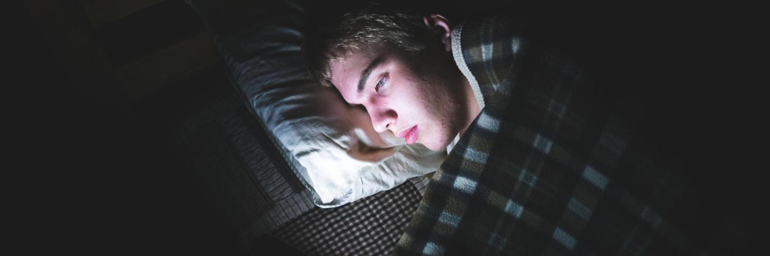 Guy staring at phone screen in bed
