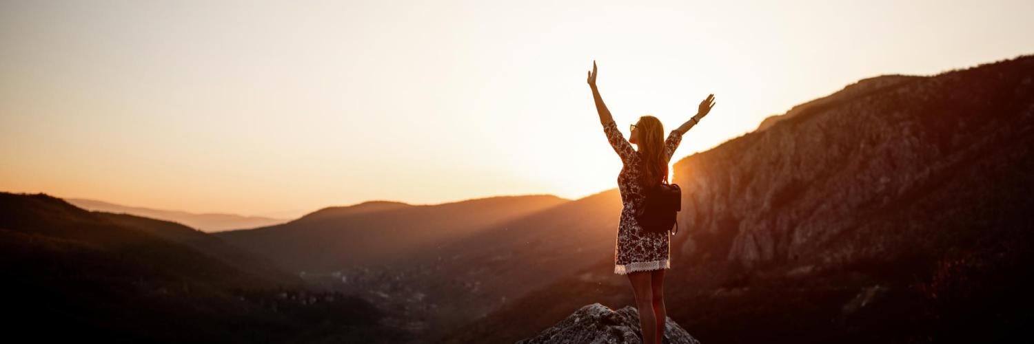 Girl standing on top of a mountain at sunset