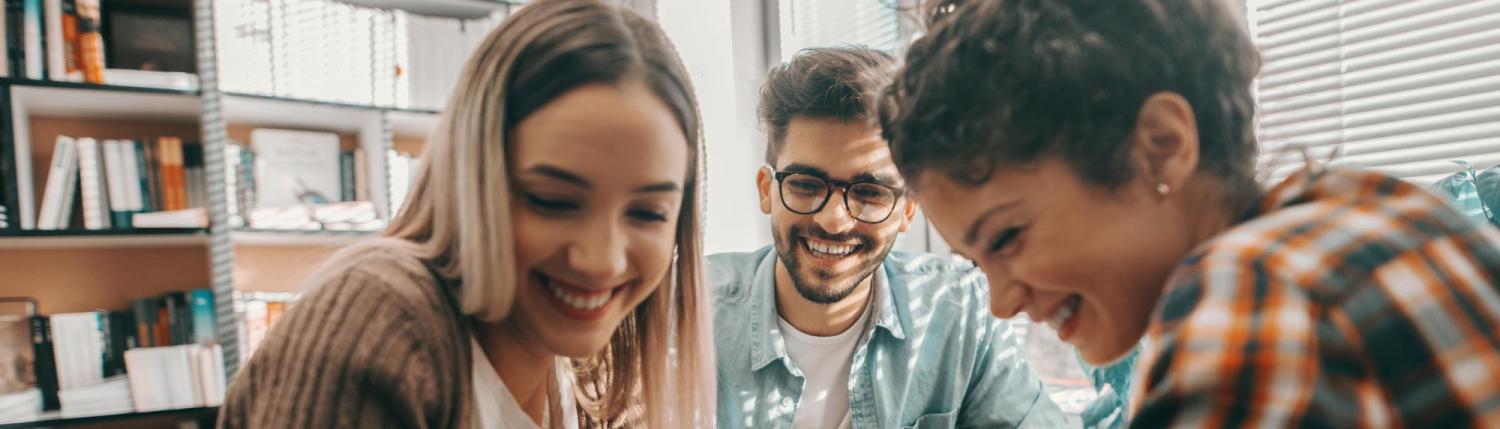 Three friends smiling and laughing together in an apartment