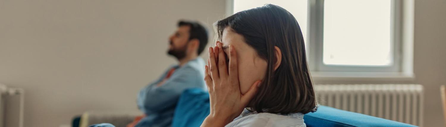 Woman and man sitting on couch with stressed expressions.