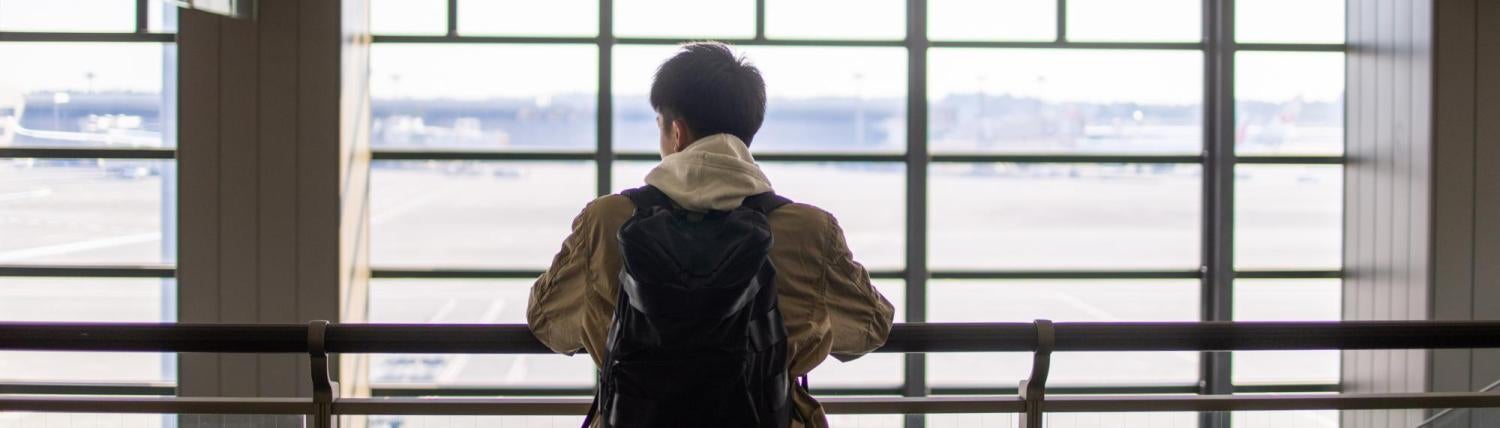 Man standing in front of bay windows at the airport