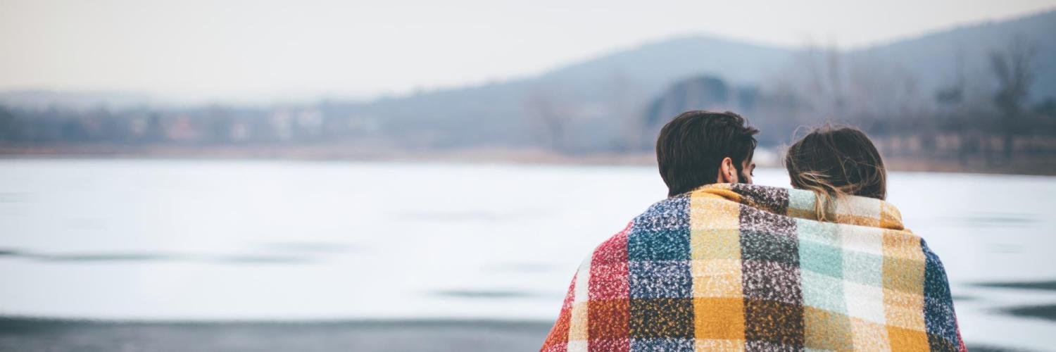 couple sitting under blanket outside in winter