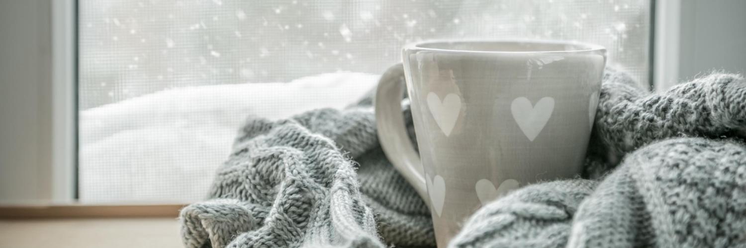 Cup of tea and blanket in front of snowy window