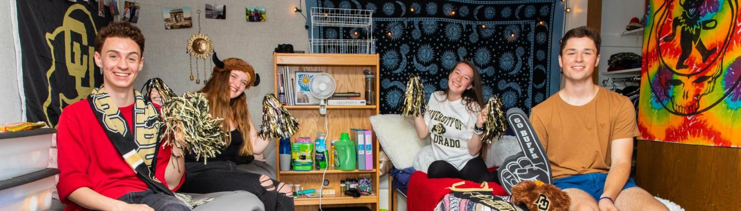Students sitting on beds in dorm room with cu boulder gear