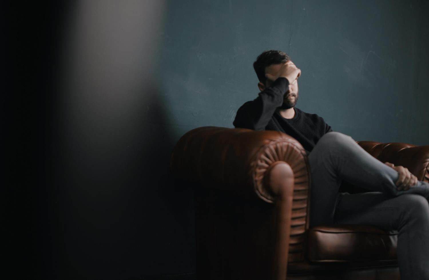 Man sitting in couch holding head