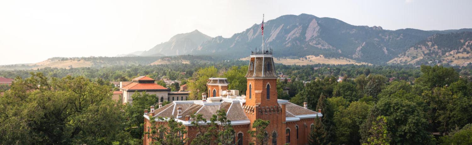 Aerial view of old main on a misty morning in spring with the flatirons in the background.