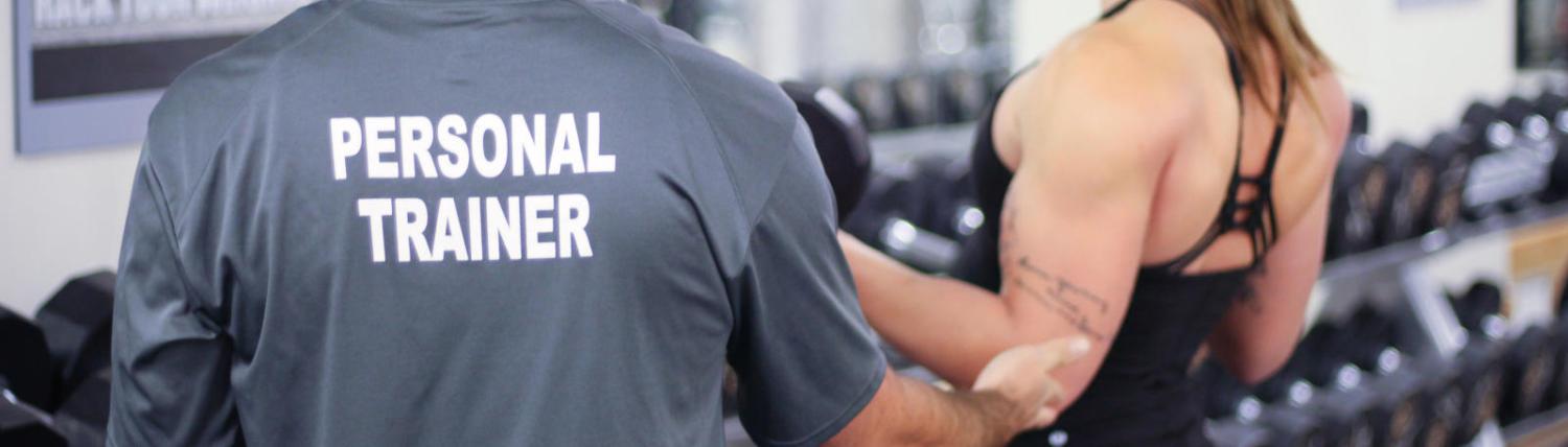 Male trainer working with female student on bicep curls