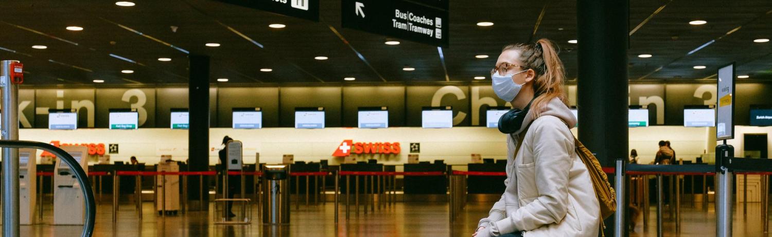 Young woman sitting on her luggage in an airport terminal.