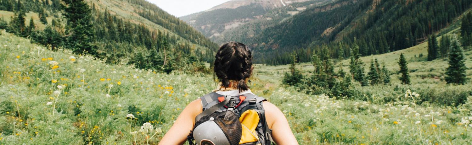 Person standing on a trail in a backpack.