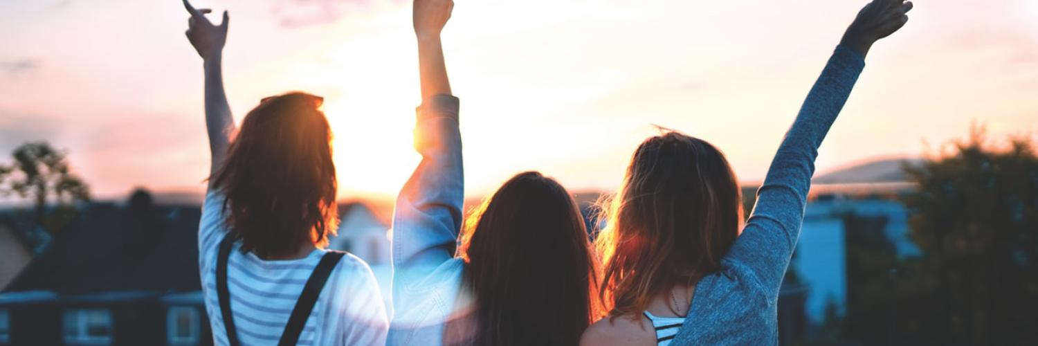 Girls standing in front of a sunset